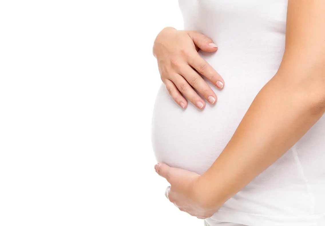 Pregnant woman gently holding her belly.