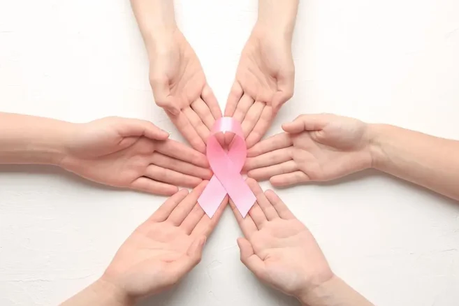 Hands holding a pink ribbon symbolising breast cancer awareness.