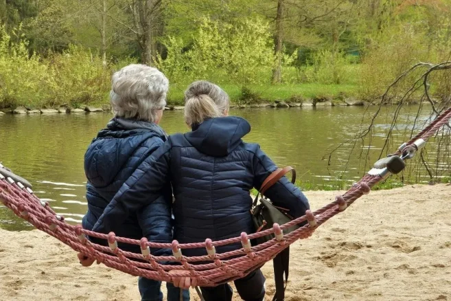 Two people sitting together beside a peaceful lake.