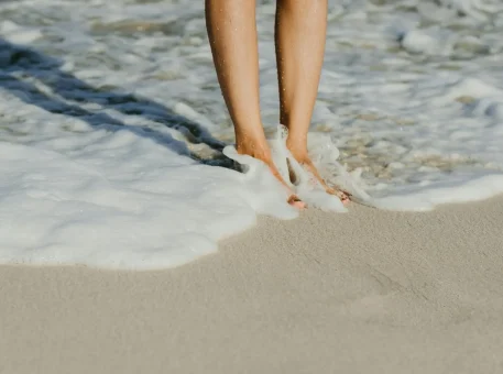 Bare feet walking along a sandy beach.